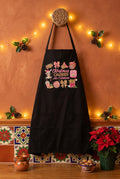 A black apron with a colorful Christmas-themed graphic and the text 'Christmas Calories No Cuentan' displayed on a knob in a Christmas themed kitchen.