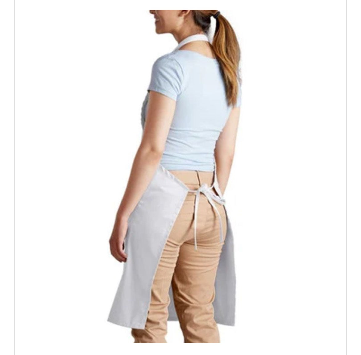 A woman shown from the back wearing a light gray kitchen apron tied around her waist over a light blue t-shirt and tan pants, against a plain white background.
