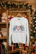 An off-white crewneck sweatshirt displayed on a mannequin torso with blue jeans. The sweatshirt features a colorful graphic of a peace sign, a pink heart, a nutcracker, a Christmas tree, and the text 'Peace Love Nutcracker'.