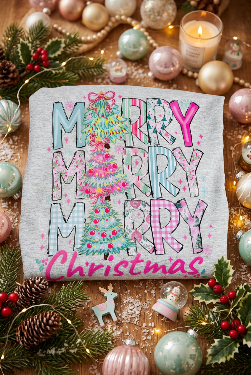 A folded light gray heather sweatshirt featuring a colorful graphic print that reads 'MERRY MERRY MERRY Christmas' with a decorated Christmas tree in the center.