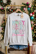 A light heather gray crewneck sweatshirt with a colorful 'Merry Merry Merry Christmas' graphic on the front, displayed on a rack with denim shorts against a white Christmas background.